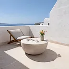 A polished concrete bowl table paired with a wooden lounger on an Aegean-inspired whitewashed balcony. Clean-lined exterior furnishings for boutique coastal villas.